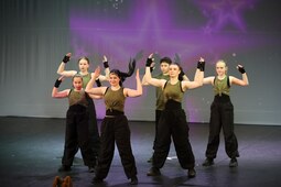 Ein Gruppe von Jugendlichen tanzt in kurzen Jeans und Karo-Hemden